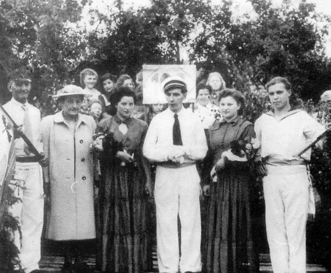 Eine Gruppe von Menschen in historischer Kleidung, die Blumen halten, steht im Freien.