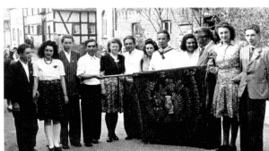 Eine Gruppe von Menschen posiert mit einer Fahne auf einer Veranstaltung in der Vergangenheit.